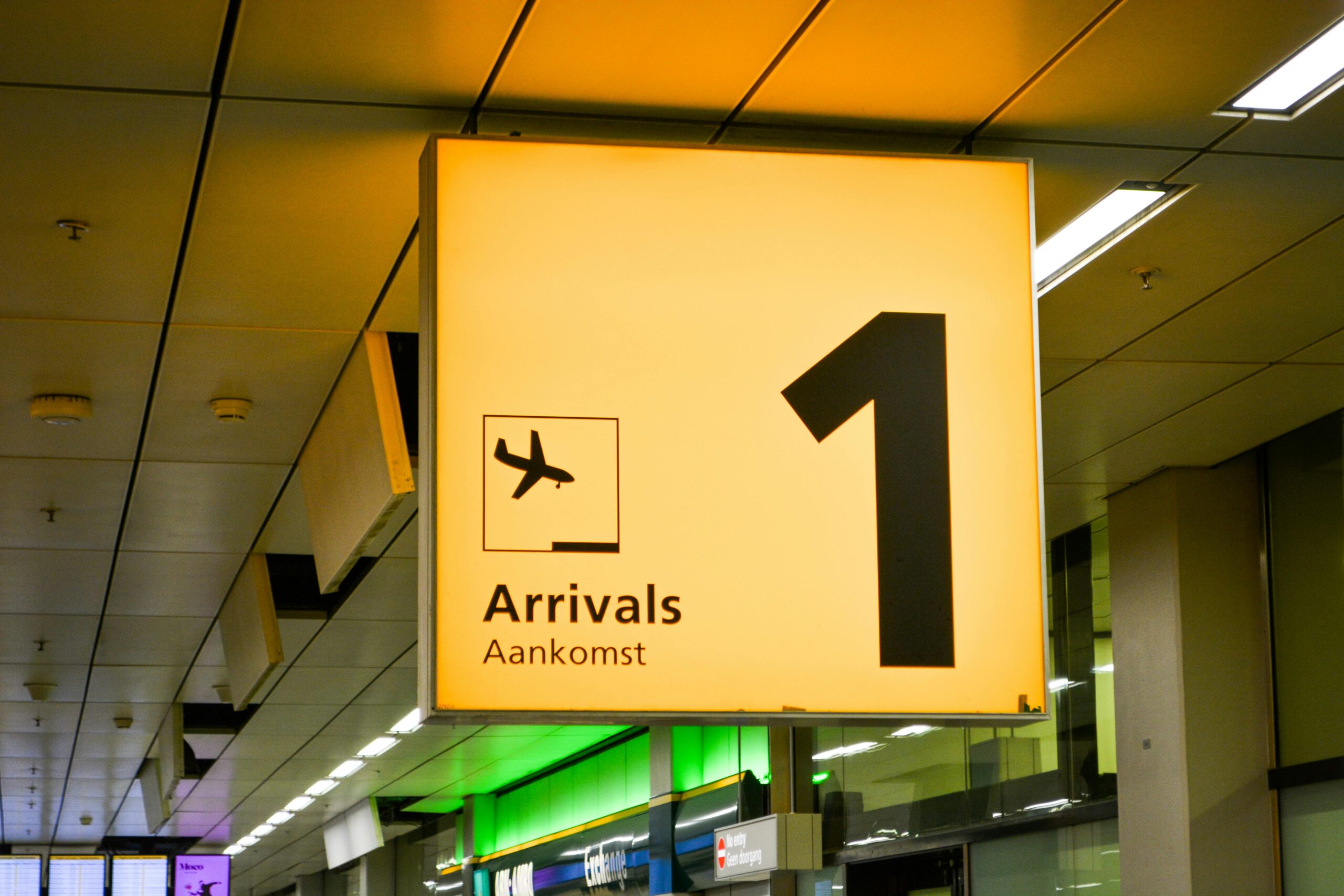 Bright arrivals sign with airplane symbol in an airport terminal.